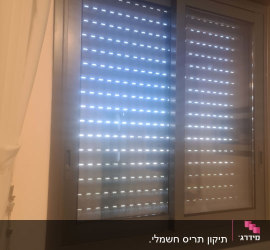תריסים סגורים עם חריצים לאור על חלון